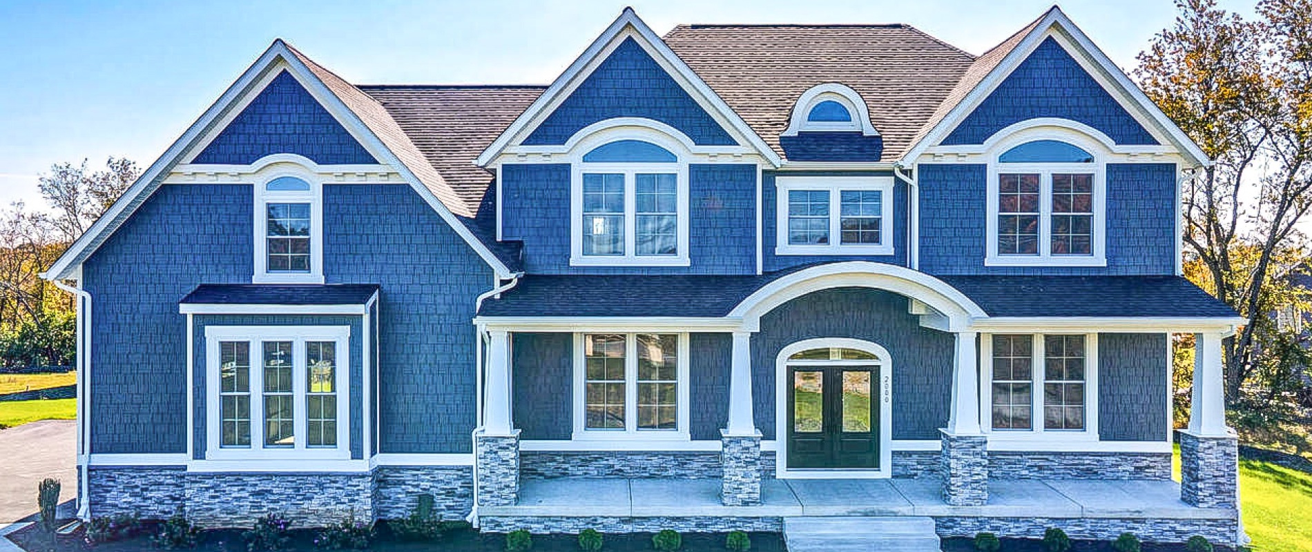 facade of custom home facade on a hill with lawn and trees